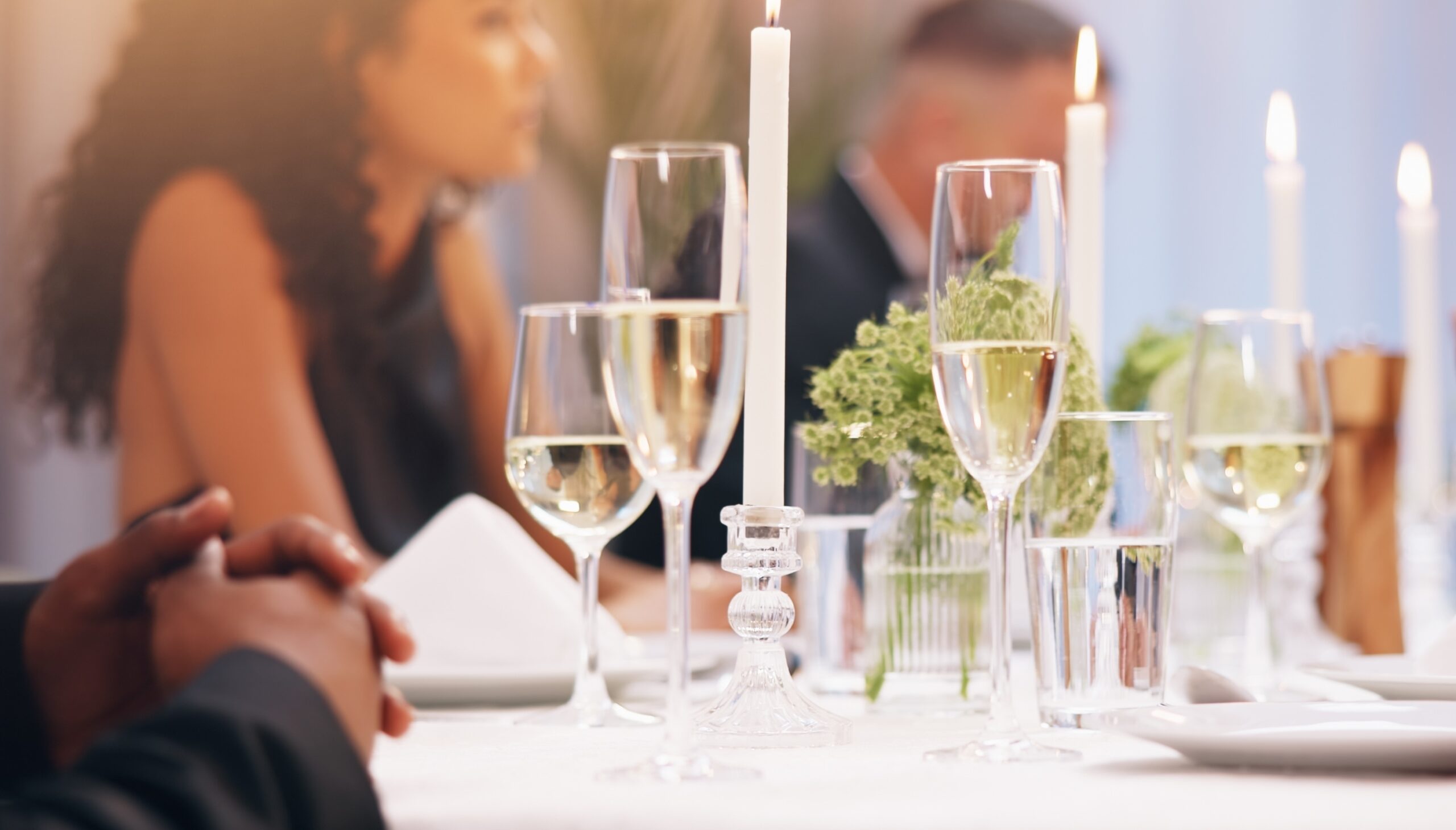 groom pouring champagne into a glass while the bride holds it
