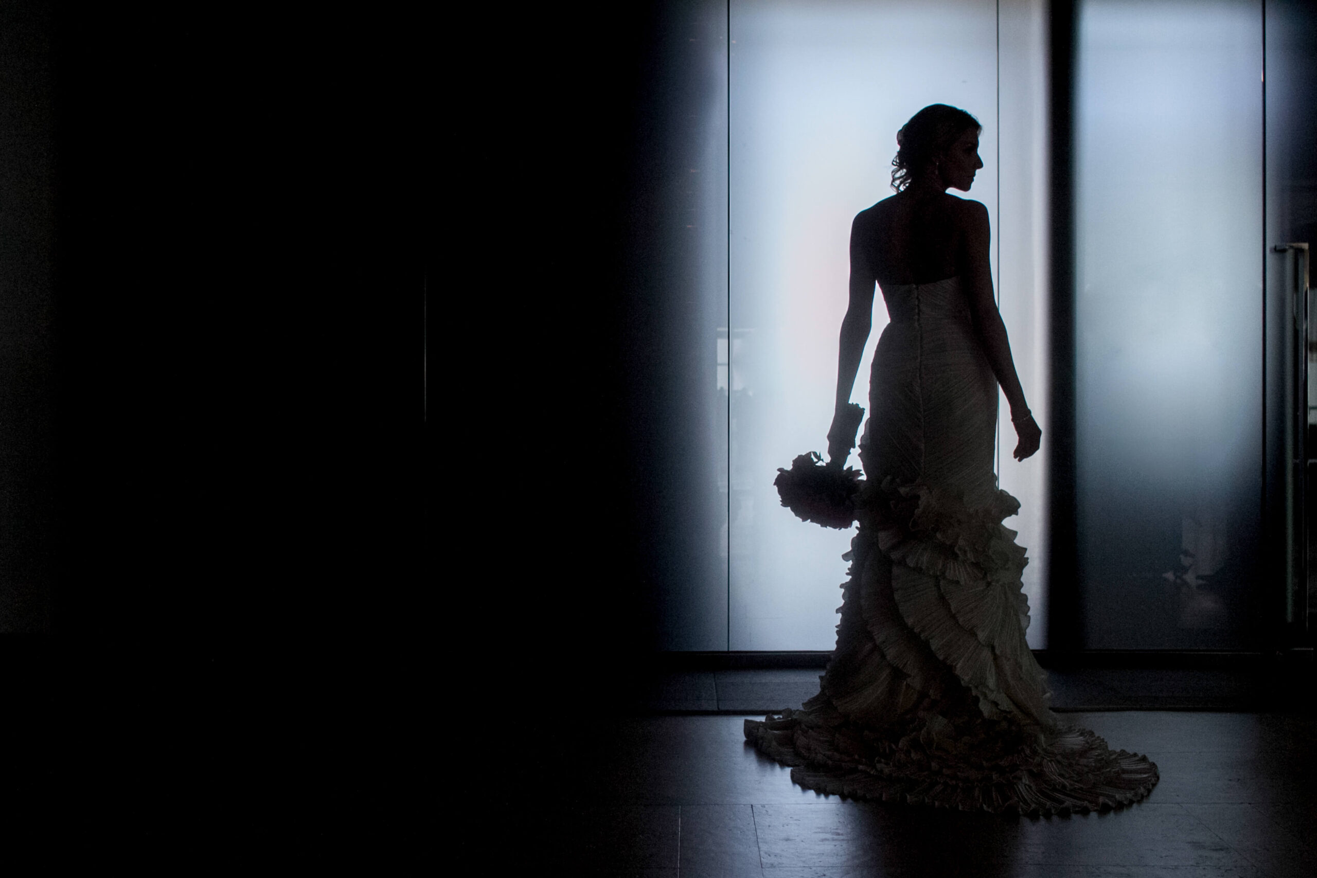 a silhouette of a bride standing in front of a window at one atlantic wedding venue