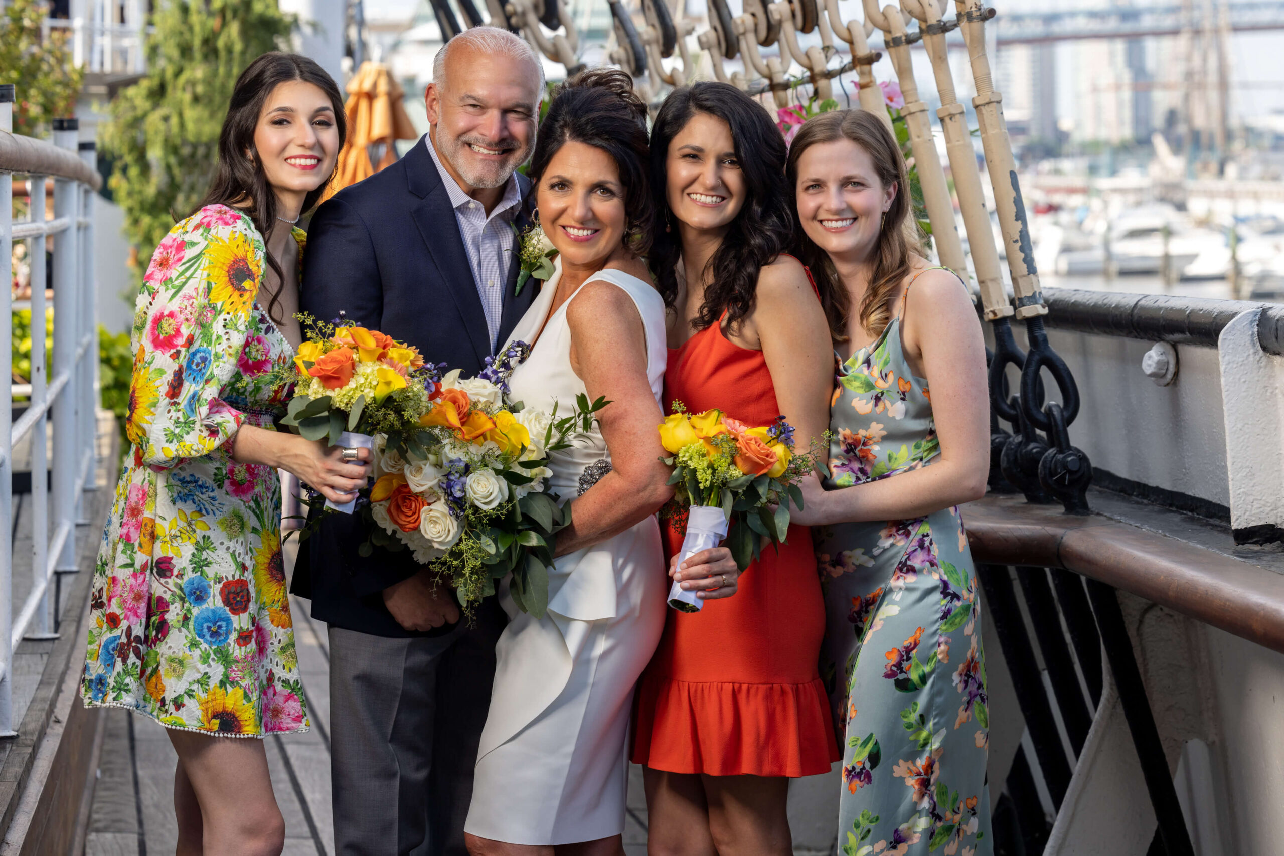 a group of people posing for a wedding photo on the deck of a boat