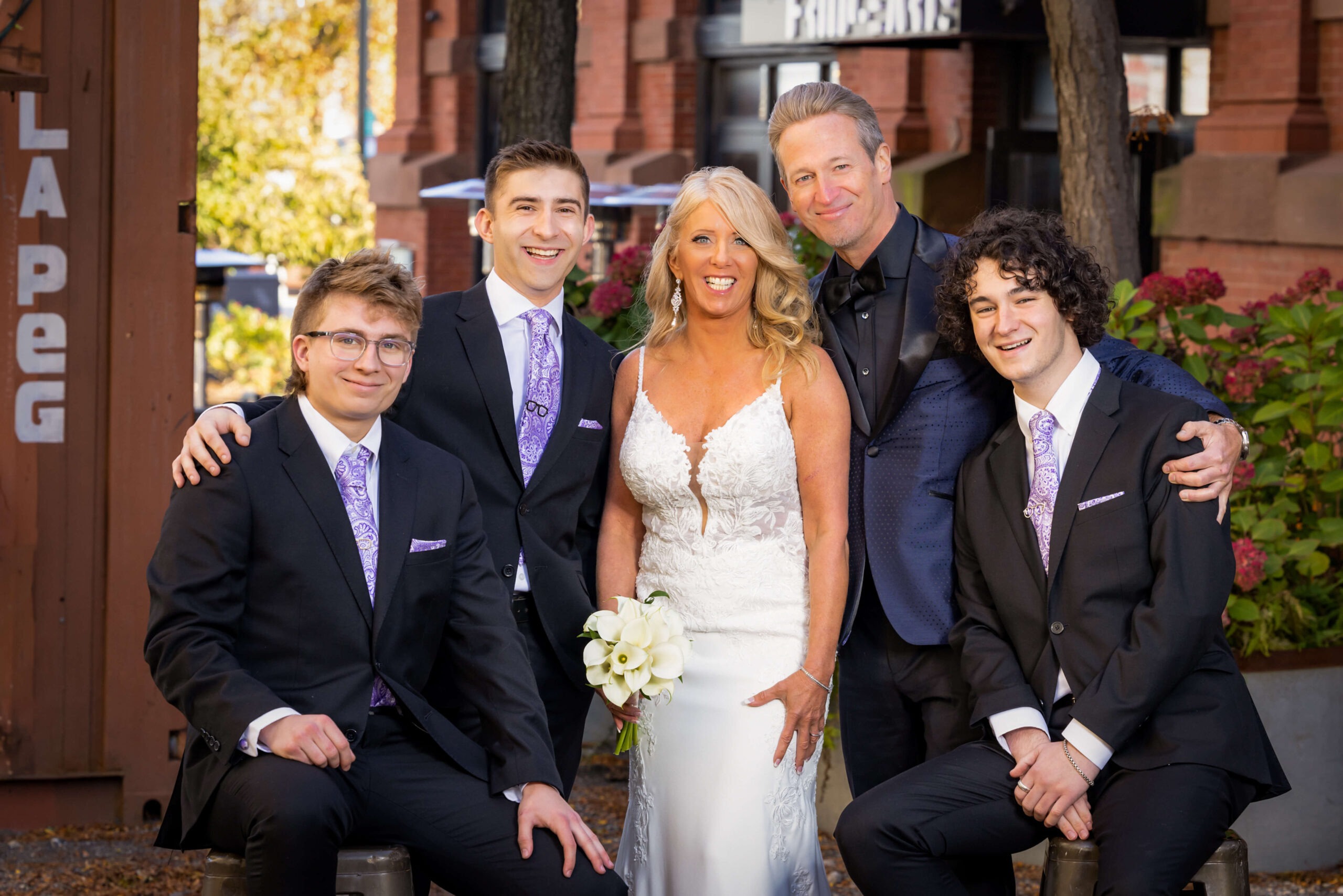 a bride and groom pose with their young men in suits