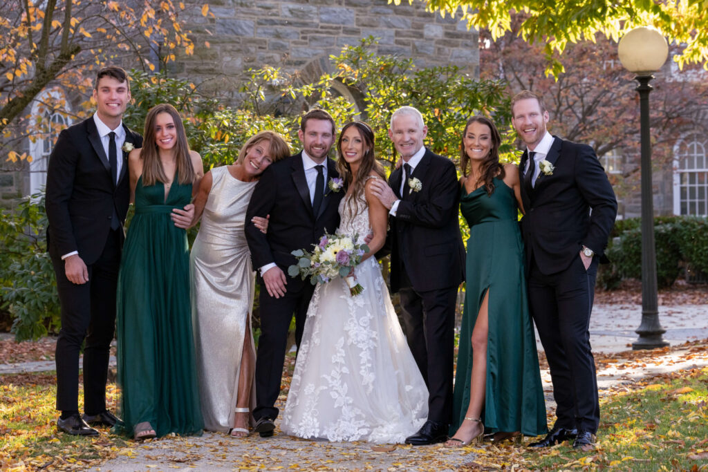 a bride and groom happily pose with their family members in front of a stone building