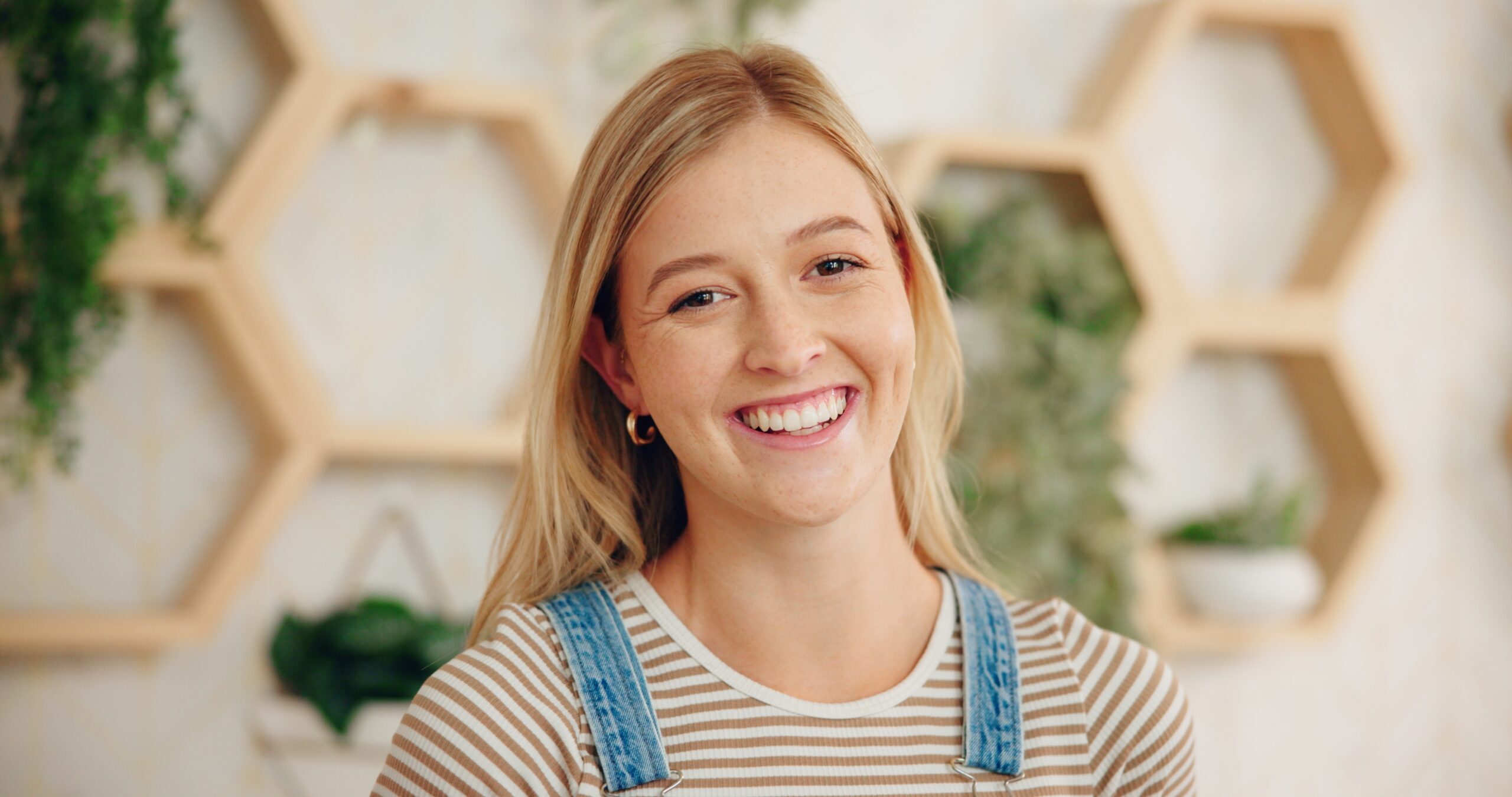 woman with blonde hair wearing a blue jacket posing against marble wall
