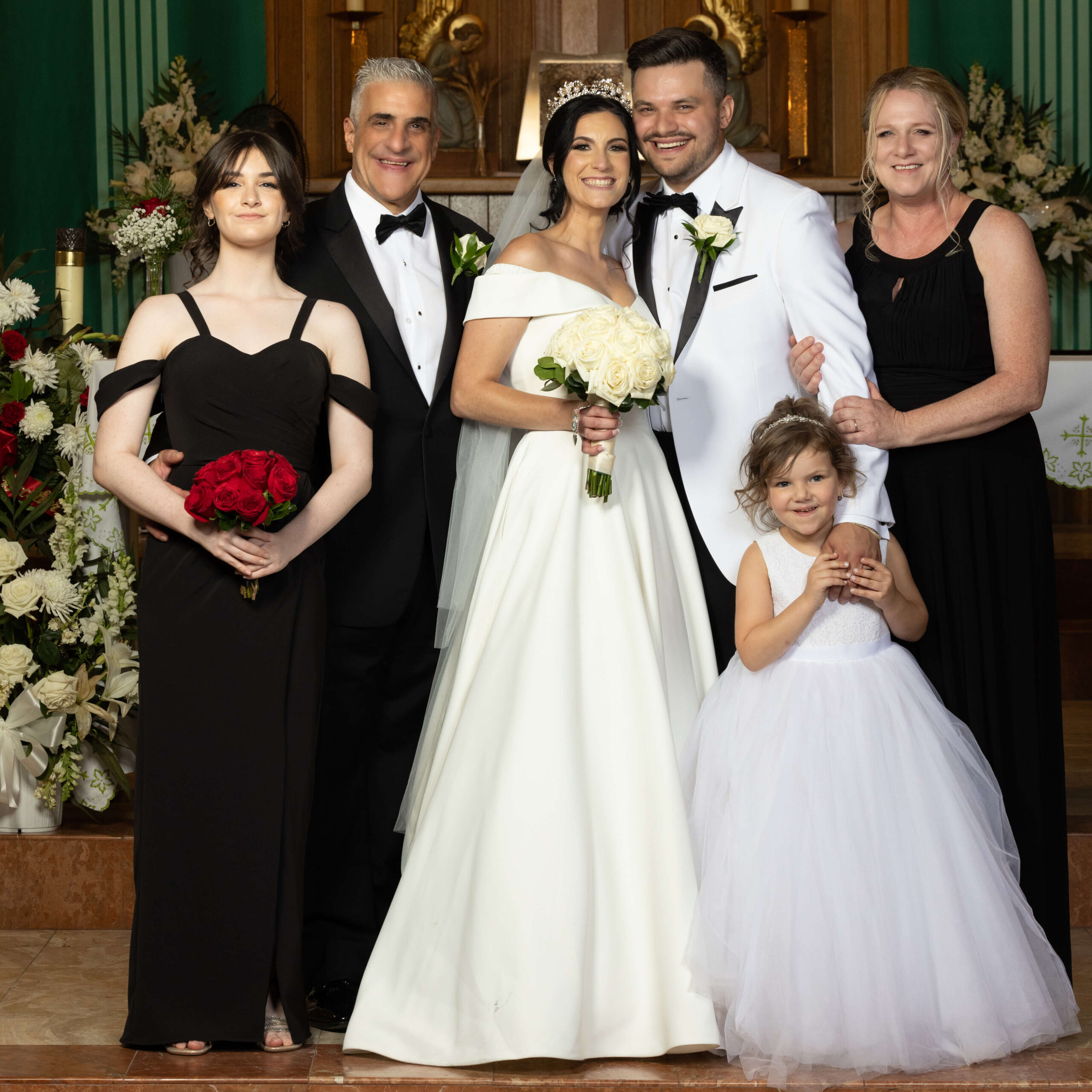 a bride and groom pose with their family in front of a church altar