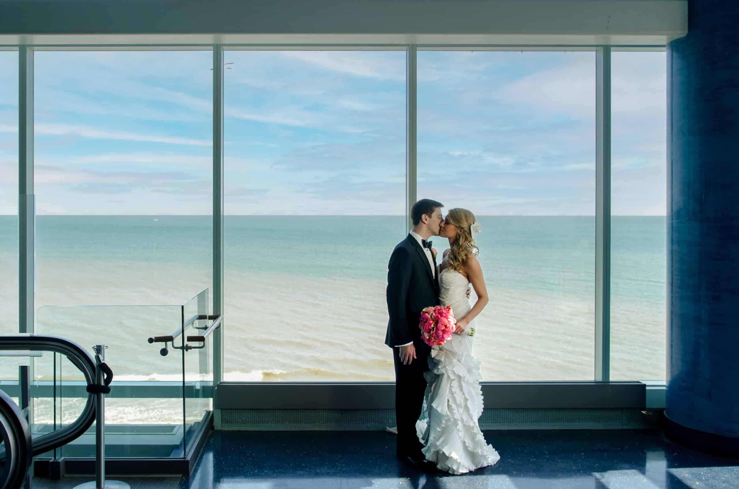 bride and groom kiss near ocean skyline