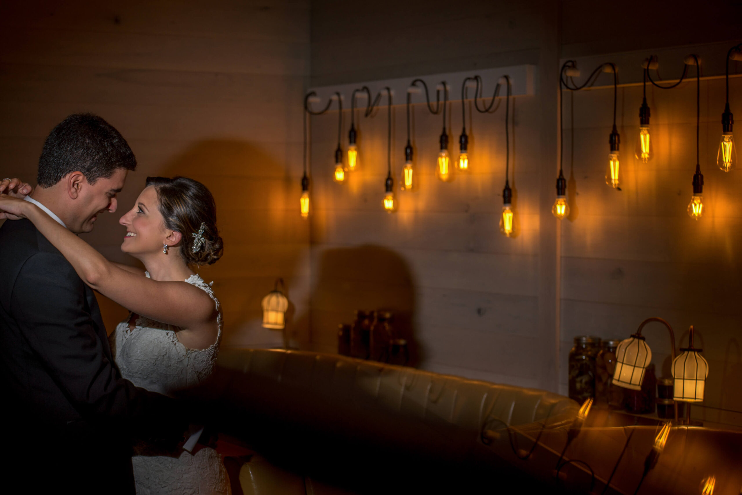 bride and groom embracing by illuminated edison lightbulbs at urban farmer in philadelphia