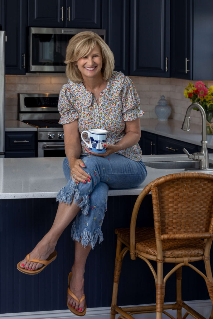 blonde woman laughing on a kitchen counter while holding a coffee mug