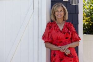 a blonde woman in a red rose dress standing in front of a white and blue shed