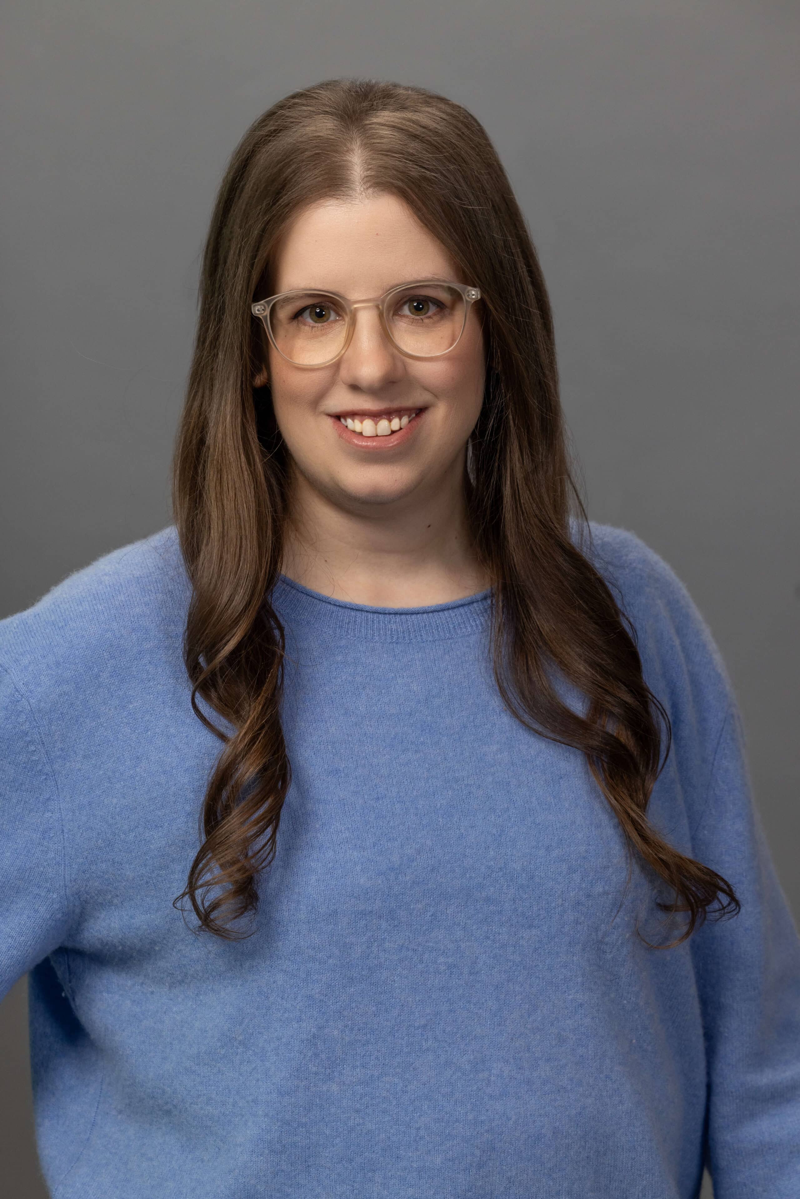 corporate woman in a blue sweater posing for a studio headshot