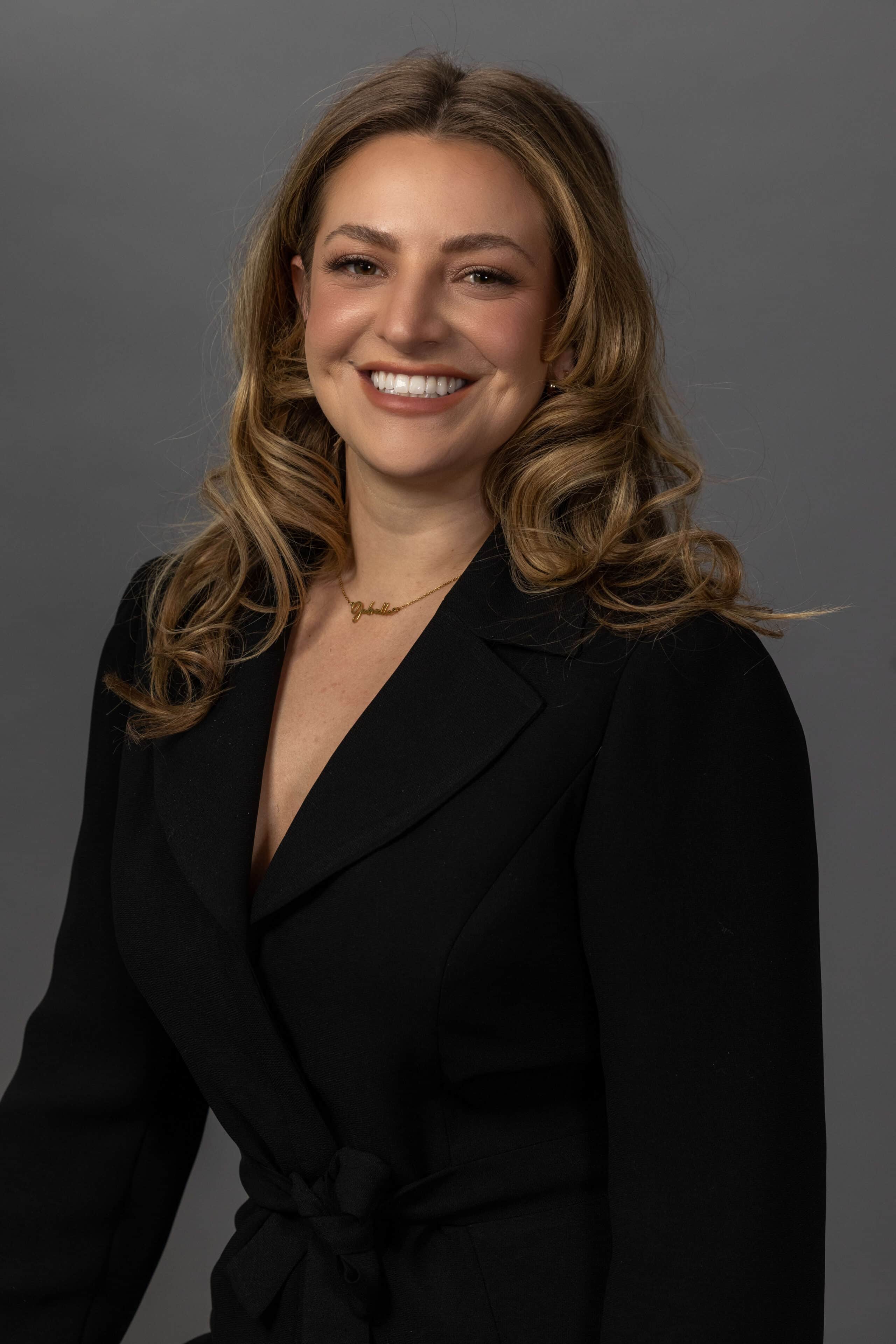 woman in all black outfit smiling for a posed headshot in the studio