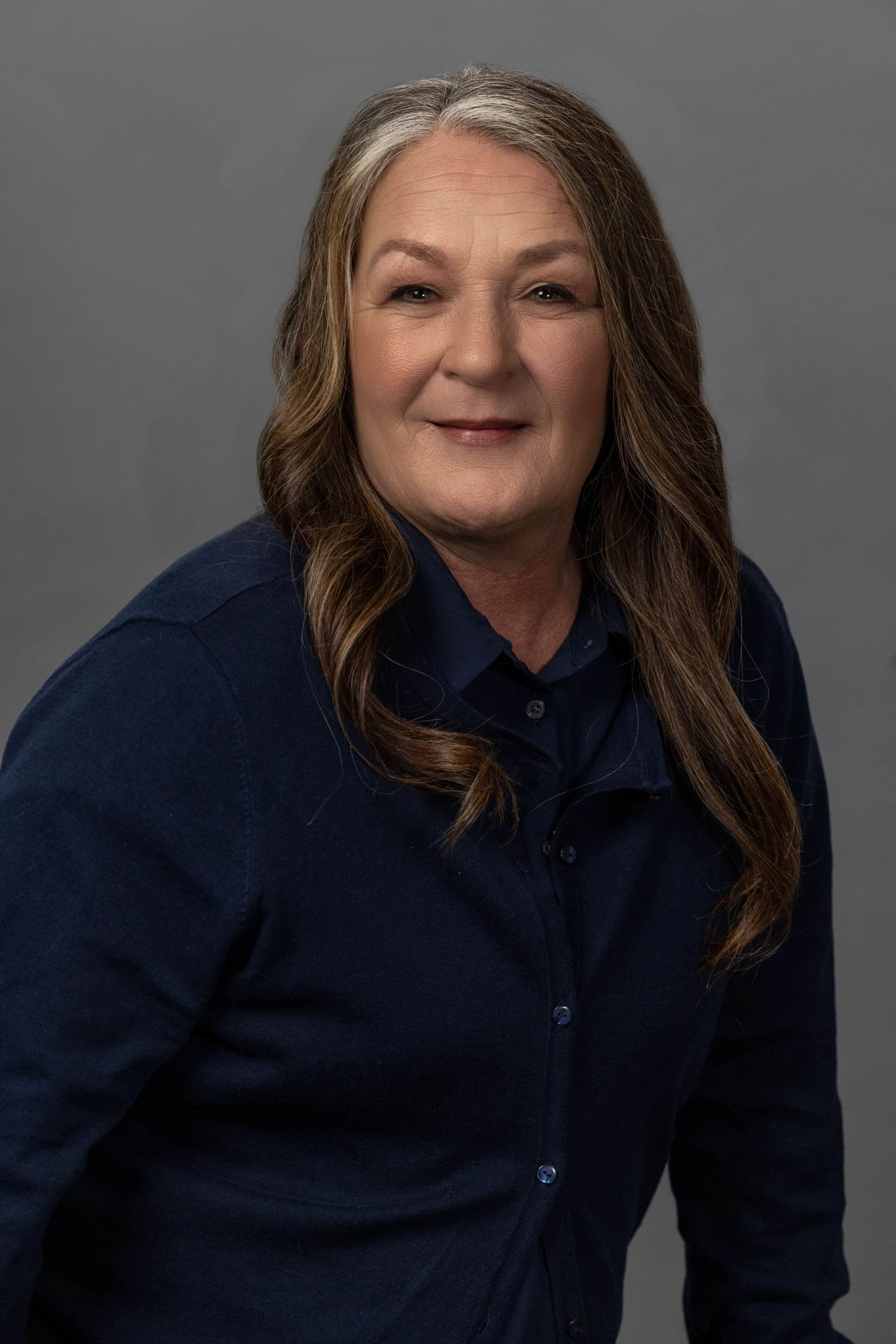 corporate woman with slight smirk against a dark gray background