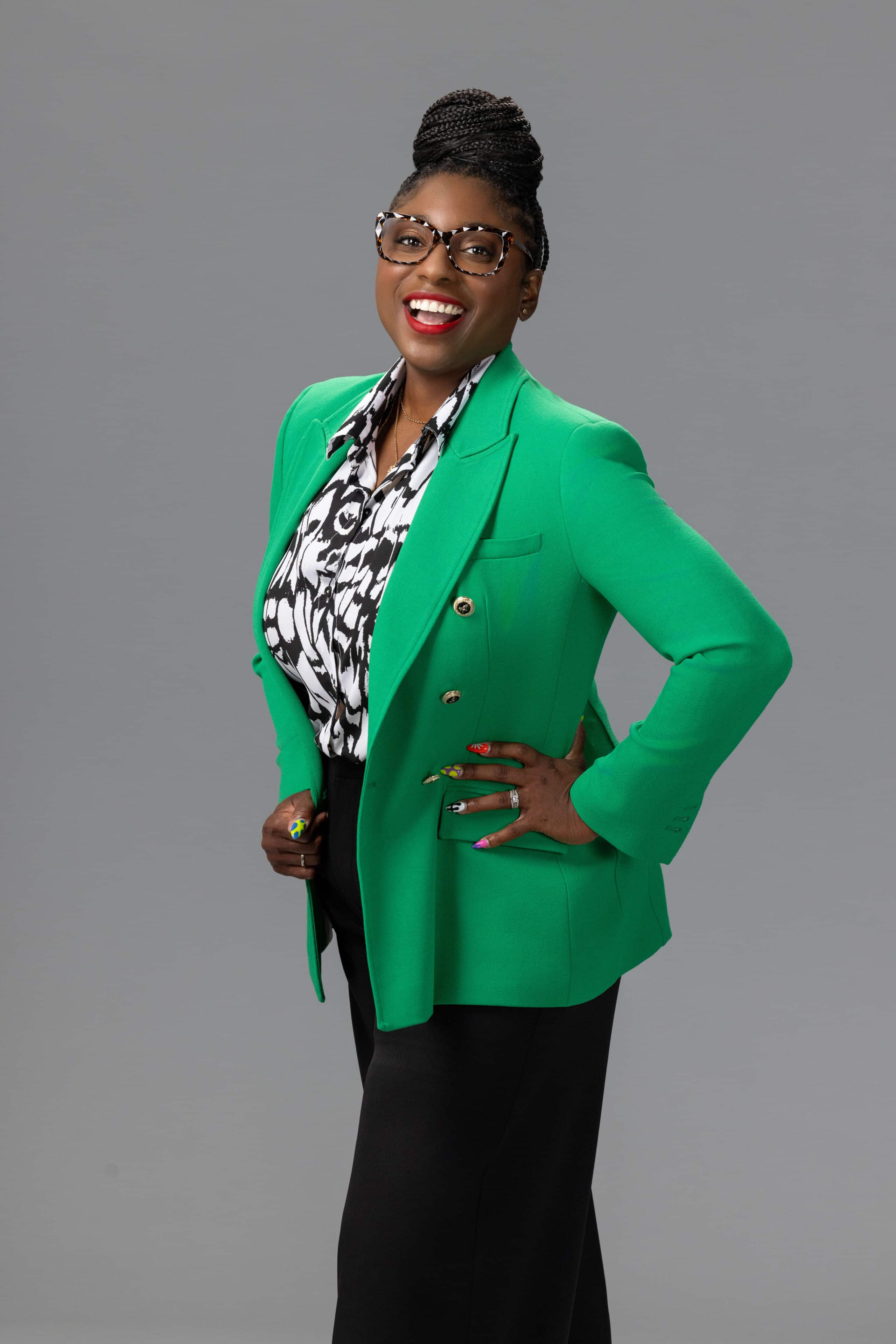 joyful woman laughing in a green jacket against a gray background