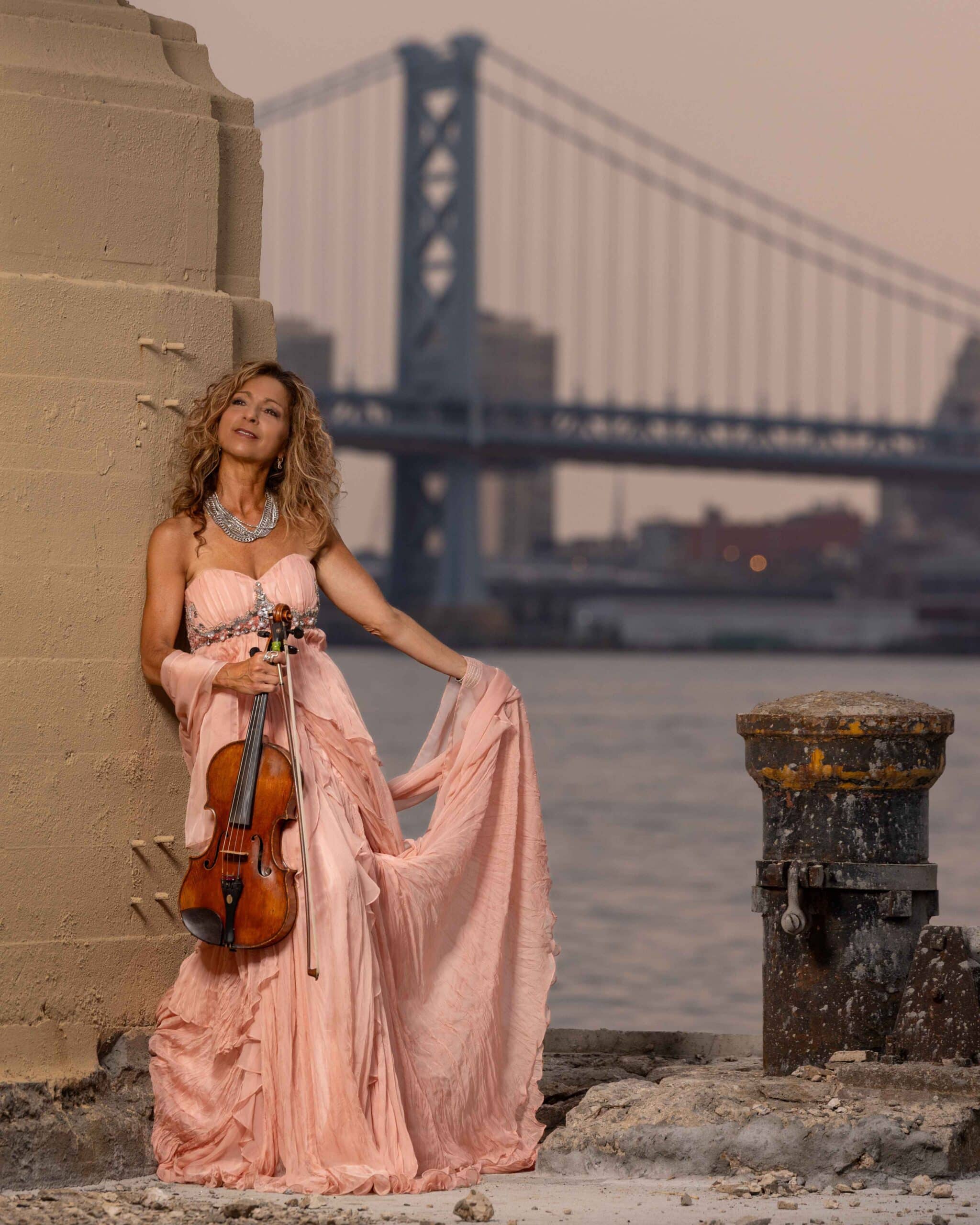 elegant woman in a pink dress holding a wooden violin