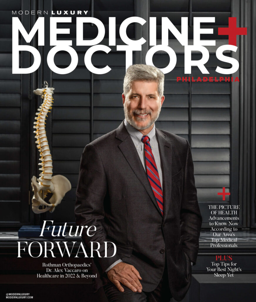 man in suit posing on a magazine cover with spine skeleton in background