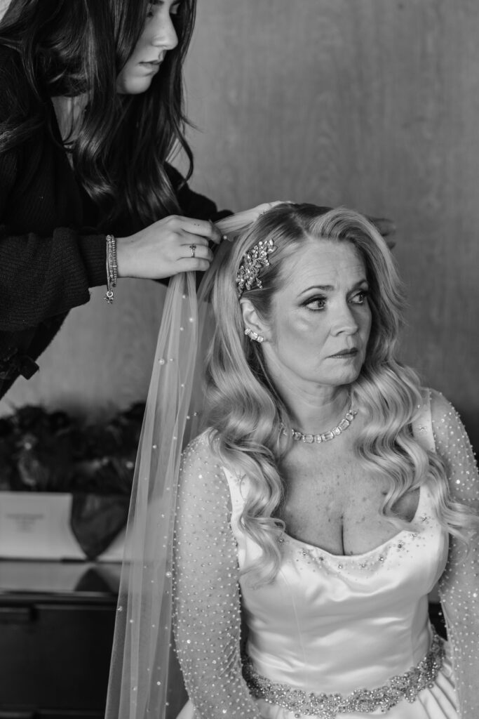 Bride having her veil adjusted by make-up artist during wedding preparation inside of a luxury Logan Hotel suite in Philadelphia