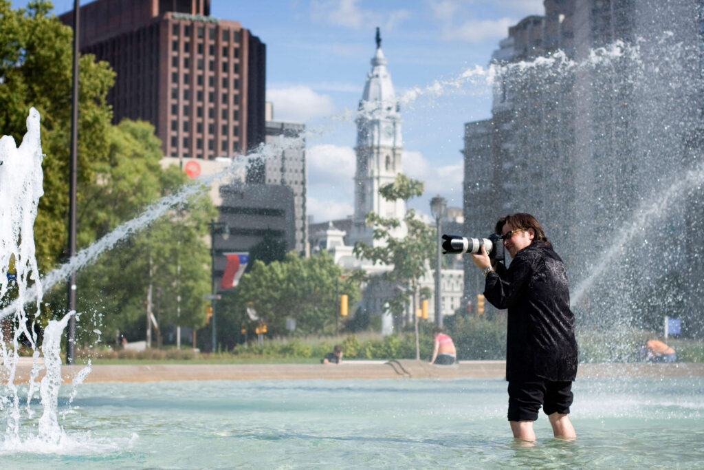 professional photographer in a water fountain at Logan Circle with Philadelphia city hall in the background