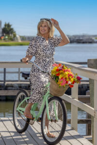 blonde woman on a light green adjusting sunglasses at the bay in avalon, new jersey