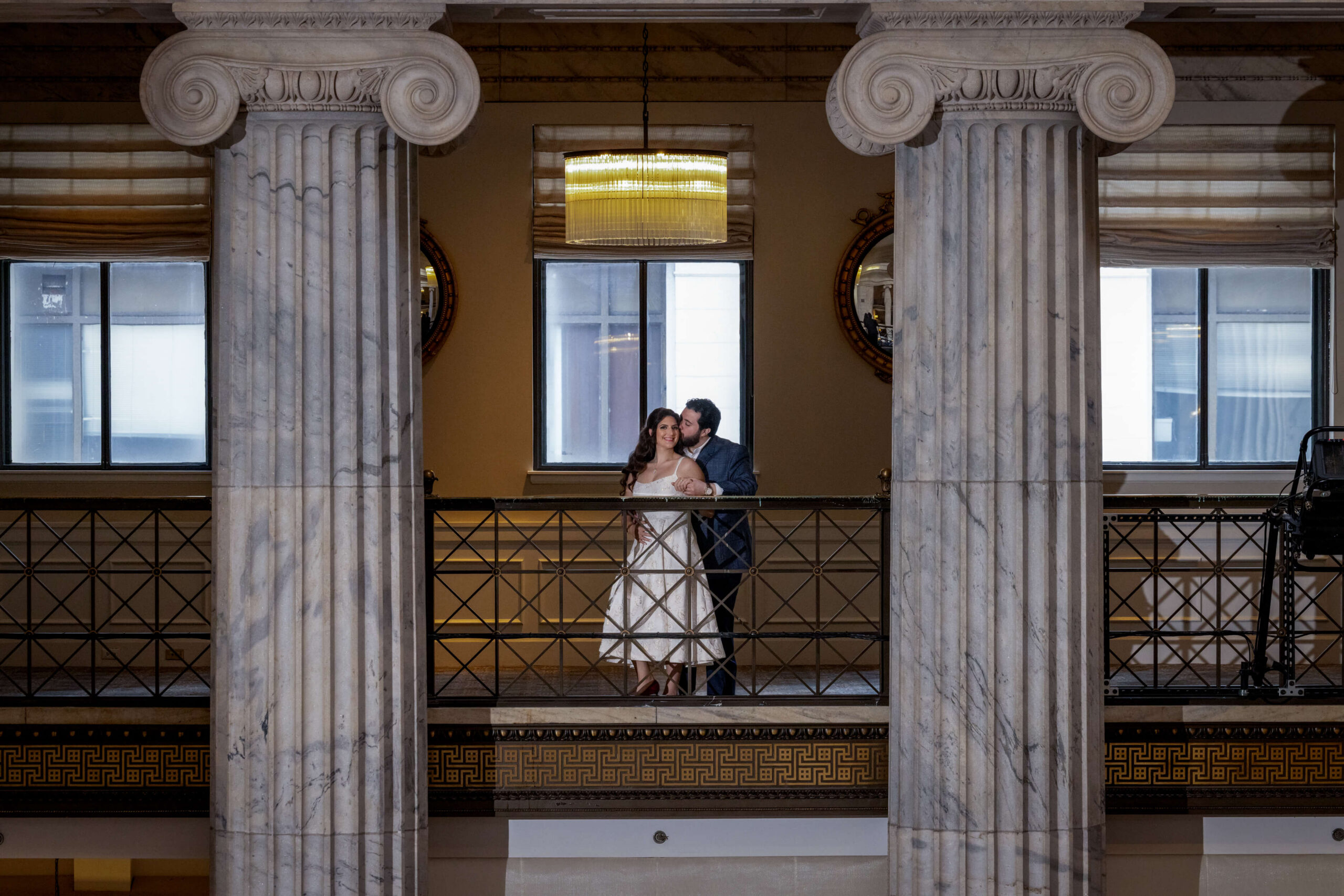 bride and groom standing over balcony at ritz carlton in philadelphia with dramatic white column architecture