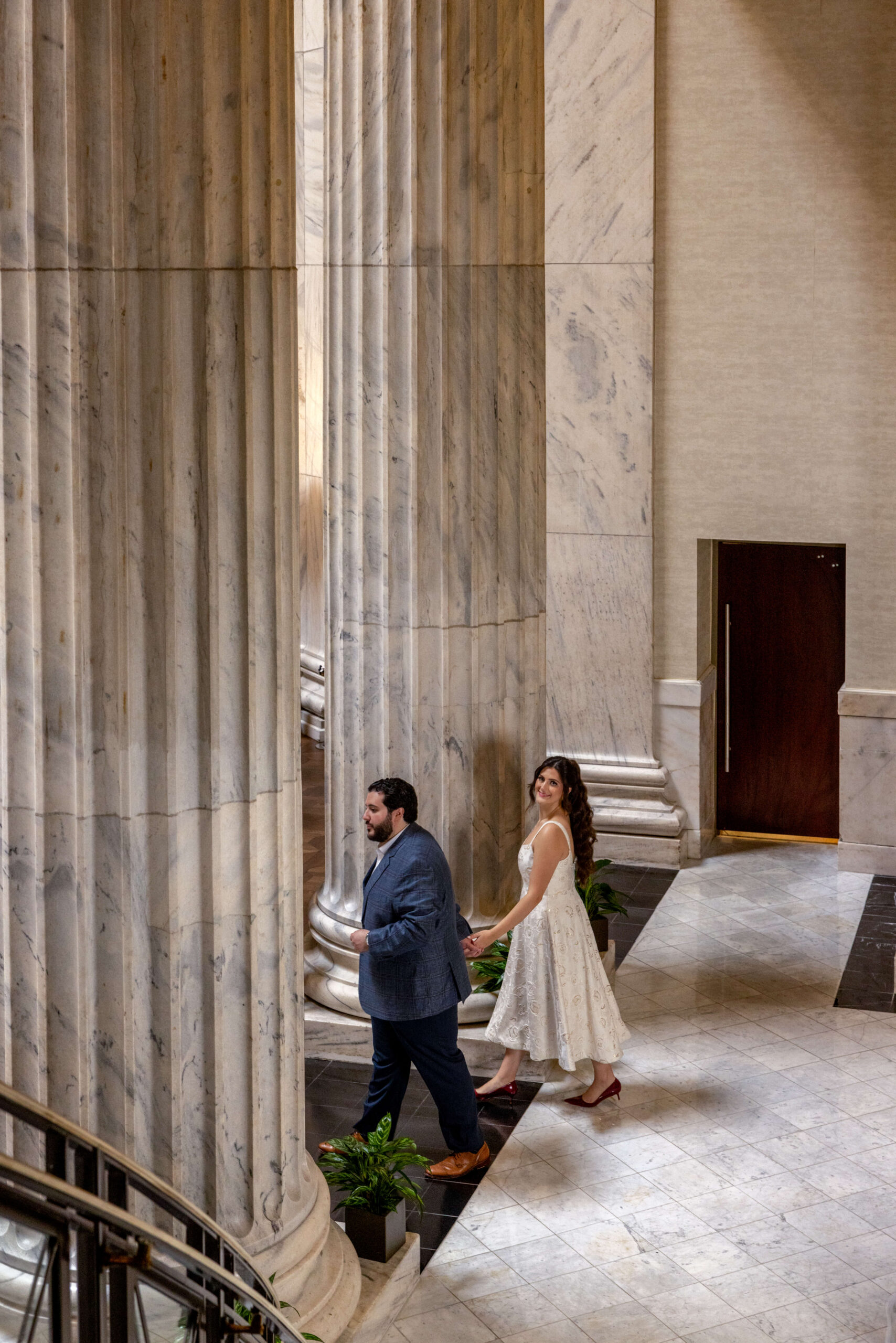 an engaged couple walking through the marble main lobby at ritz carlton in philly