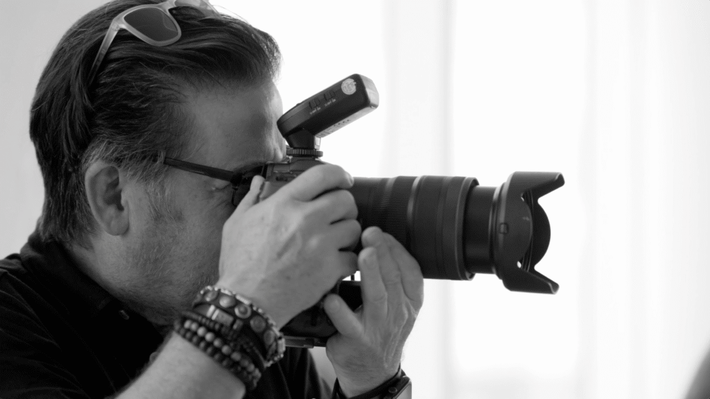black and white photo of a photographer looking into a canon camera and shooting
