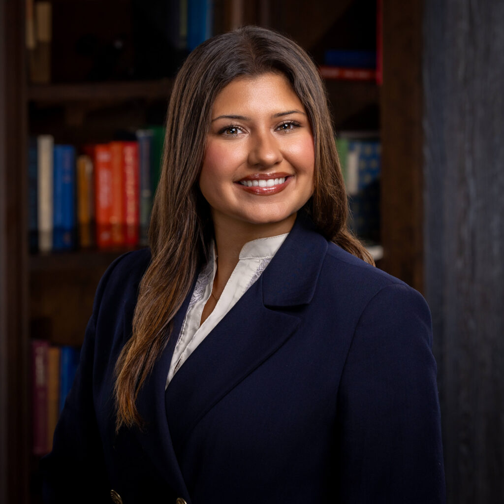 confident and professional woman wearing a sleek blue blazer jacket posing for headshot photos in a cozy library setting