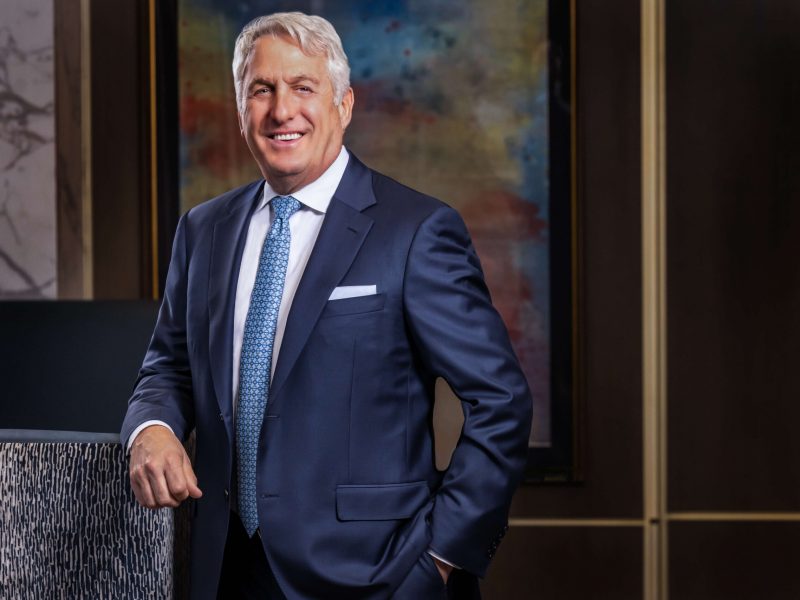 man smiling in classic navy blue suit against abstract painting