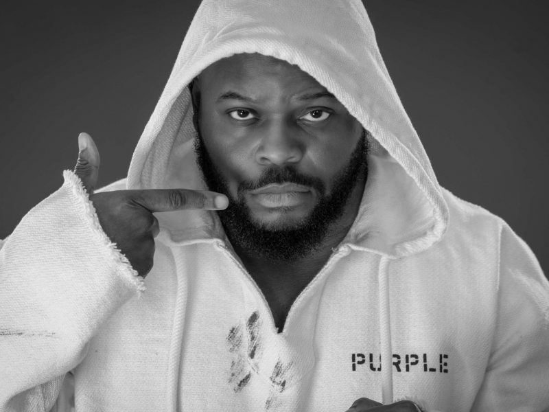 man with black beard in white hoodie pointing a gun finger gesture in front of face