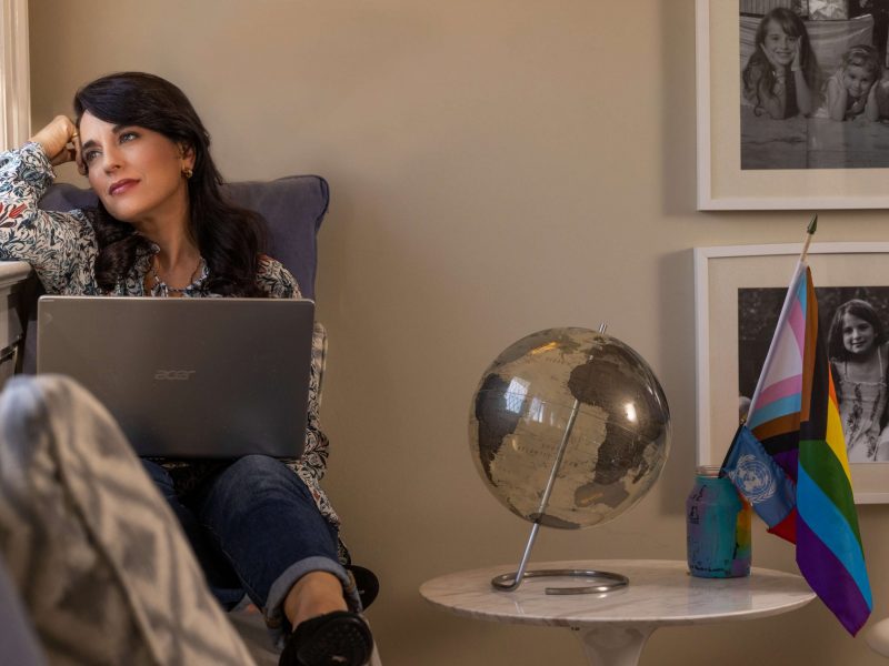 woman looking out window in family room with computer on lap
