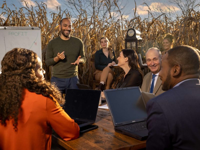 group of men and women talking at business meeting in cornfield