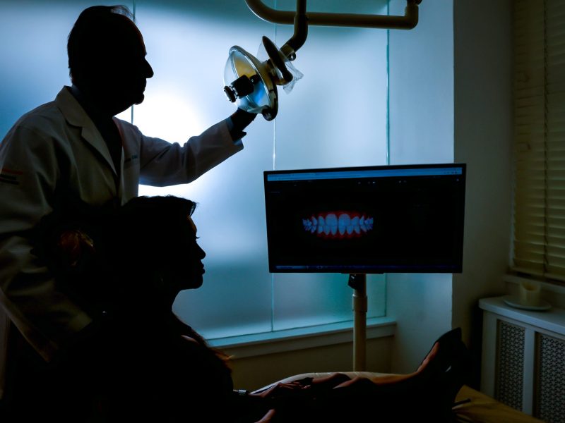dentist in dark room with monitor and surgical light