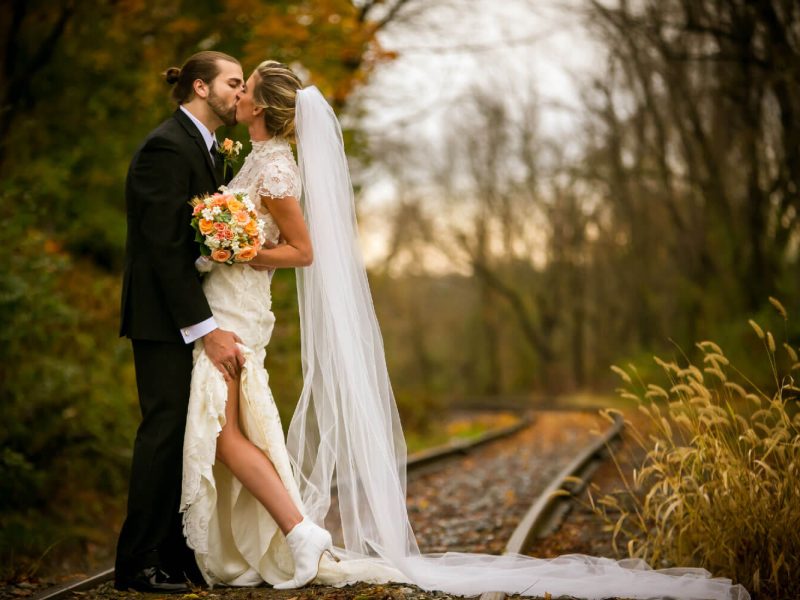 bride and groom kissing at train tracks